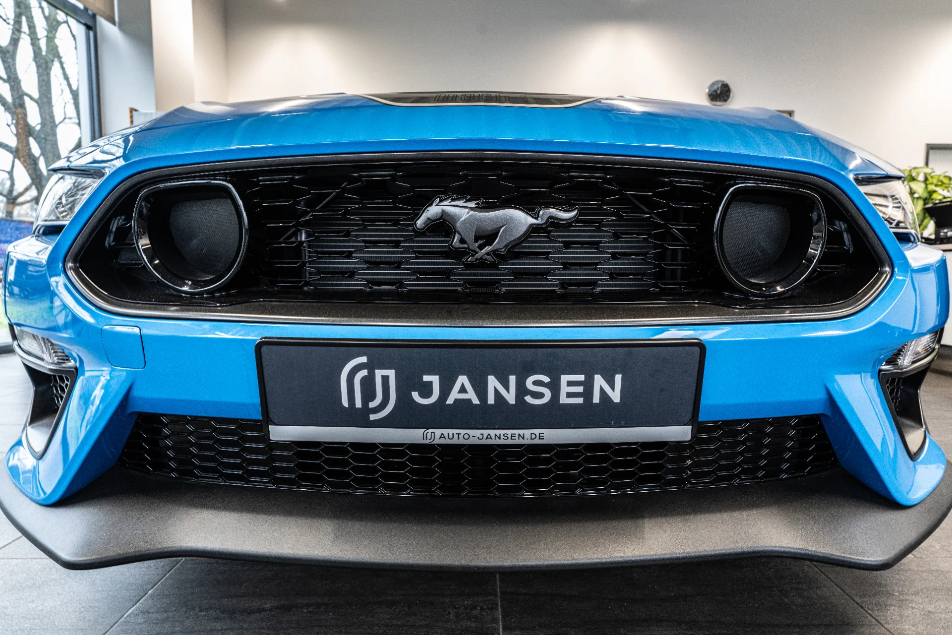 Frontansicht eines blauen Ford Mustang mit schwarzem Kühlergrill und Mustang-Logo im Autohaus Jansen