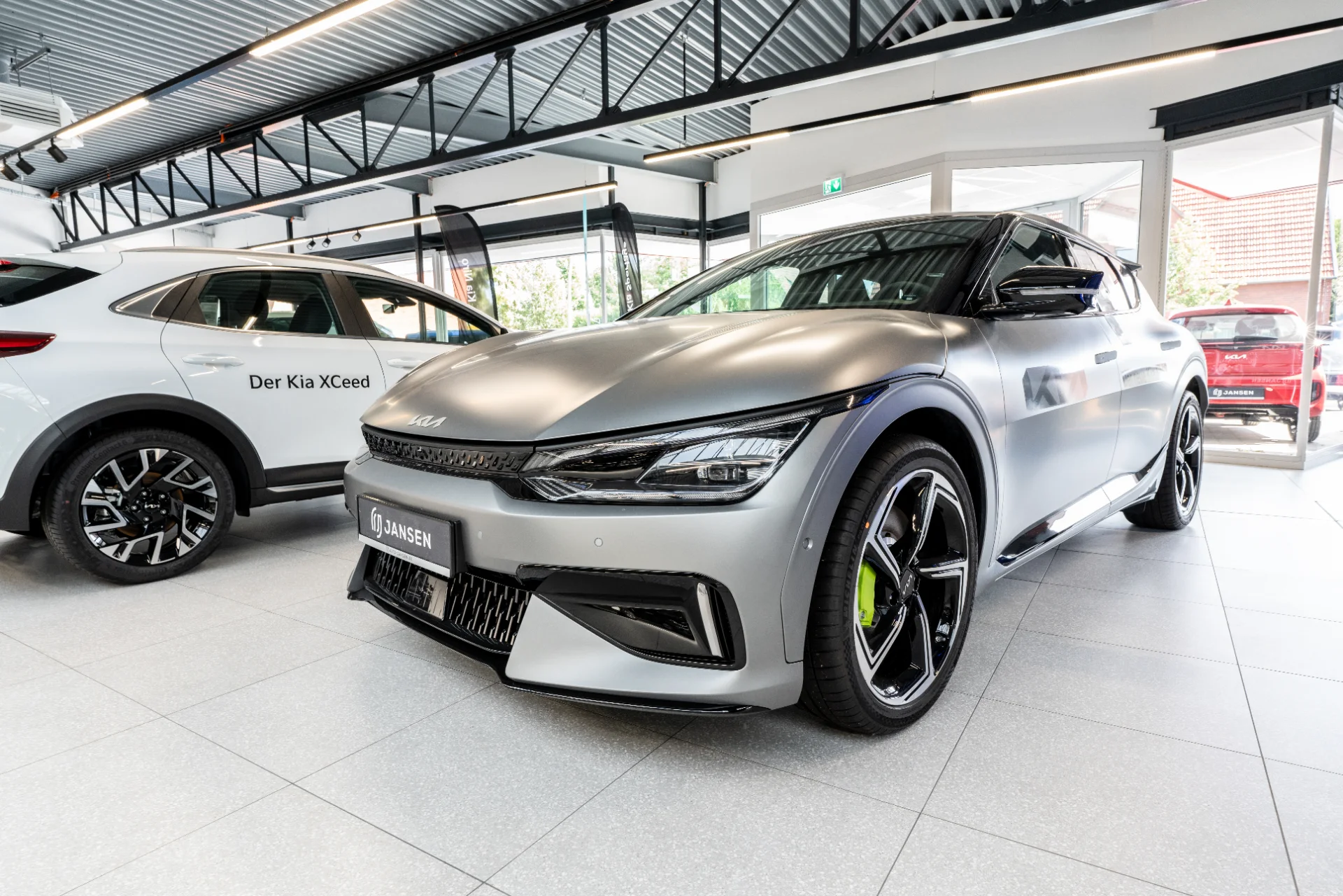 Kia EV6 in Silber im Autohaus Jansen, daneben ein weißer Kia XCeed im Showroom